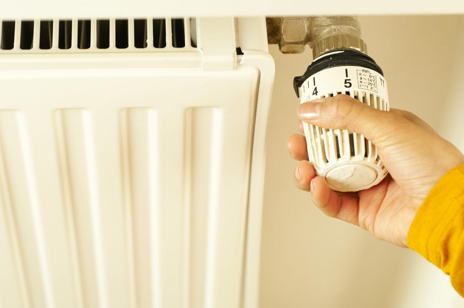 Hand adjusting a thermostatic valve on a home radiator