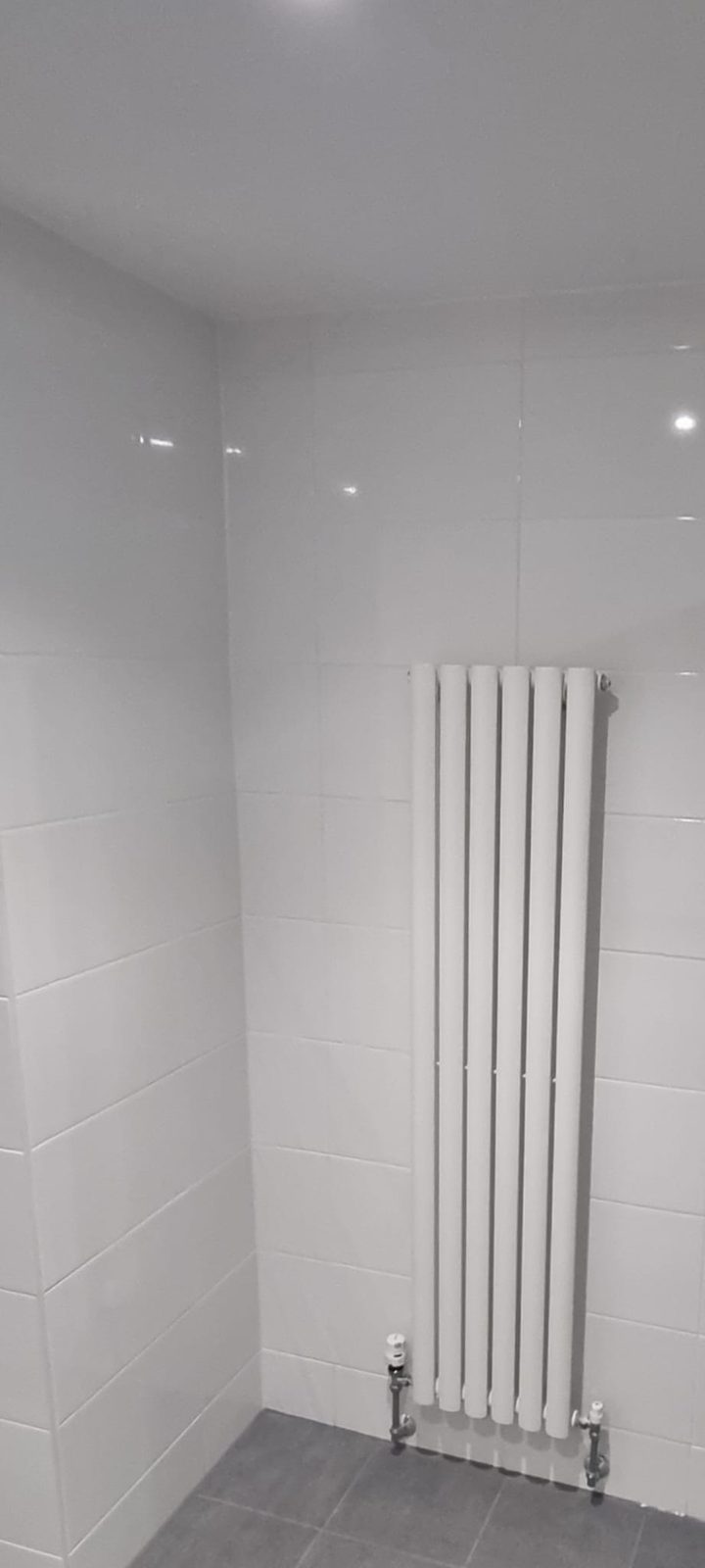 Vertical column radiator fitted in a newly tiled bathroom